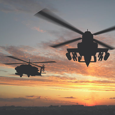 Two helicopters flying at sunset